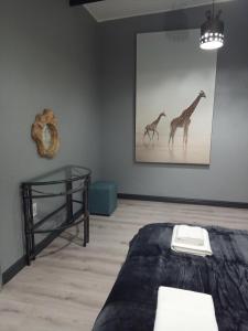 塔巴津比Woodpecker Villa Guesthouse的一间房间,配有一张床和一张两幅长颈鹿的照片