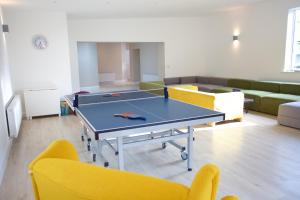 RiverstownRock House Sligo的配有黄椅的房间的乒乓球桌