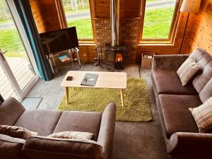 皮特洛赫里Kinnaird Woodland Lodges的客厅设有两张沙发和一个壁炉