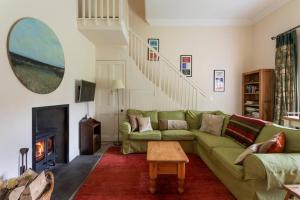 斯特灵Old Leckie Farmstay的客厅设有绿色沙发和壁炉
