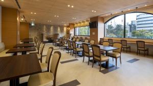 广岛Dormy Inn Hiroshima Annex的餐厅设有桌椅和大窗户。