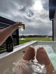 班特里Wild Hideaways Luxury Lodges and Eco Spa的在热水浴缸中喝一杯葡萄酒的人