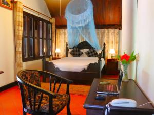 琅勃拉邦Namkhan View Luangprabang Resort的一间卧室配有一张床和一张带笔记本电脑的书桌