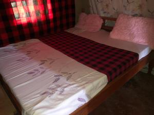 内罗毕Kiharas Farm stay的一张带红黑床单的小床