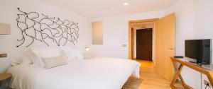 Garganta de los MontesHotel Rural Quercus Tierra的卧室配有白色的床和平面电视。