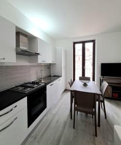 圣安吉罗山Casa Junno的白色的厨房配有桌子和炉灶。 顶部烤箱