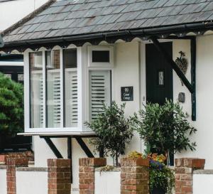 灵伍德Corner Cottage - character, charm, great location.的白色的房子,有窗户和黑色的门