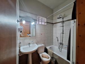 卡拉内拉Skourgias Rooms的浴室配有盥洗盆、卫生间和浴缸。
