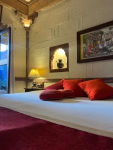焦特布尔Raj Mandir Boutique Home Stay的一间卧室配有一张带红色枕头的大床