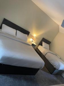 斯凯里斯The great escape的一间卧室配有两张带白色床单和枕头的床。