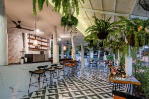 清迈花语岸·度假酒店(H·Flora Hotel)的一间种有植物的餐厅和一间设有凳子的酒吧