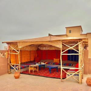 梅尔祖卡Riad Hassi Labied Merzouga的一个带五颜六色的桌椅的木制凉亭