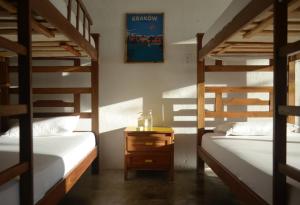 圣玛尔塔Playa del Ritmo Beach Hostel & Bar - Adults Only的客房设有两张双层床和一张带床头柜的桌子。