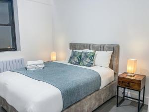 史云顿Swindon City Centre Apartments by Elegance Living的一间卧室配有一张床和一张带两盏灯的桌子。