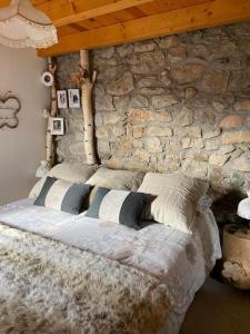OlopteIdílico refugio de montaña ideal escapadas的一间卧室设有石墙和一张带枕头的床。