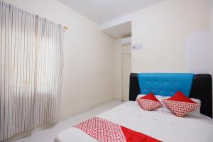 名古屋OYO 93130 Baloi Homestay的一间卧室配有红色和白色枕头的床