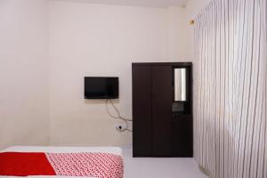 名古屋OYO 93130 Baloi Homestay的一间卧室配有一张床,墙上配有电视