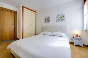 西尔米奥奈Appartamenti Anna的白色的卧室设有一张白色的大床和一扇门