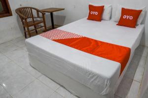 SedatiOYO 93161 Nurul Hikmah Homestay Syariah & Sport Center的一张带橙色和白色床单的床和椅子