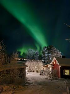 ÖverkalixArctic Circle Cabin的红谷仓上方的天空中闪烁着极光