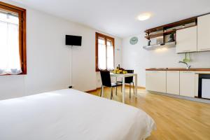 西尔米奥奈Appartamenti Anna的白色的客房设有一张床铺和一张桌子以及一间厨房。