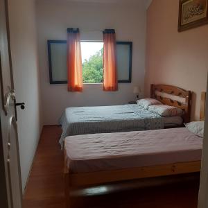 恩布Embu Manacás da Serra的一间卧室设有两张床,窗户配有橙色窗帘
