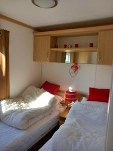 PortknockieMelody Brooks Caravan Park Caravan number 22的一间卧室配有两张床和一张带台灯的桌子