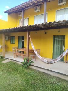 布希奥斯Pousada Alto da Marina的外面设有吊床的黄色房子