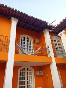 塞古罗港POUSADA DAS FLORES的橙色的建筑,设有白色的窗户和阳台