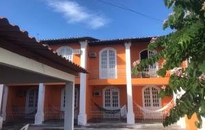 塞古罗港POUSADA DAS FLORES的一座橙色的建筑,设有白色的窗户和栅栏