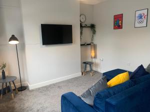 Great WyrleyCannock - 2 large bedroom house for work & leisure的客厅配有蓝色的沙发和平面电视。