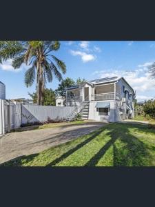 布里斯班197 Shafston Ave Kangaroo Point QLD 4169的白色的房子,有棕榈树和围栏