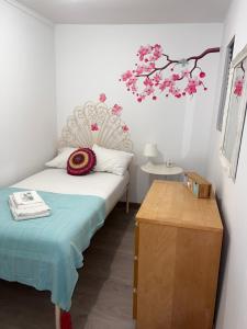 帕苏迪阿尔库什Apartamento com escada e pátio, em frente praia的一间卧室配有一张床,另一处是粉红色花朵的树枝
