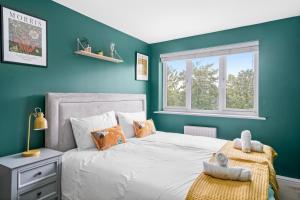 WoolstoneBeautiful 2 Bedroom Apartment MK Free Parking的一间卧室配有一张蓝色墙壁的床和一扇窗户