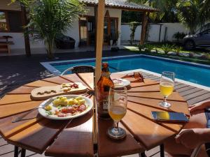 托兰克索Casa Harmonia, com 5 suítes em Trancoso-BA的一张桌子,旁边是游泳池,摆放着食物和饮料