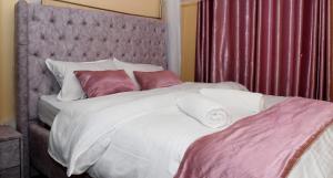 基苏木Intellicents Apartments的卧室配有一张带白色床单和枕头的大床。