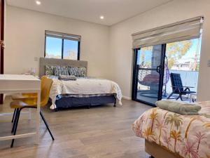 悉尼Penshurst Guest House的一间卧室配有一张床、一张桌子和一个窗户。