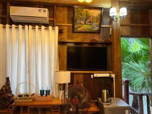 吉仙猫田河度假村的客厅配有电视和带风扇的桌子。
