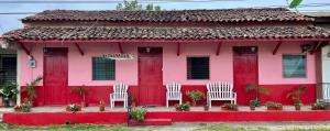 Los SantosHostal Voyager La Villa de Los Santos, Panama的粉红色的房子前面有白色的椅子