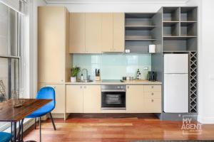 墨尔本Melbourne Bourke Street Bliss的厨房配有白色橱柜、桌子和蓝色椅子