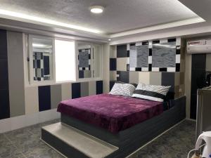 波尔多·格尼拉Anak Jay Ang的一间卧室配有一张紫色床和条纹墙