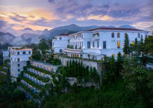 萨帕Silk Path Grand Sapa Resort & Spa的山丘上的建筑,背景是山脉