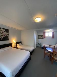 Barham相思玫瑰汽车旅馆的酒店客房设有两张床和一张桌子。