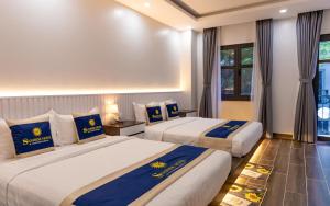 Bạc LiêuSUNRISE Hotel Bạc Liêu的两张位于酒店客房的床,配有蓝色和黄色枕头