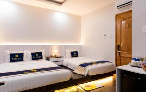 Bạc LiêuSUNRISE Hotel Bạc Liêu的酒店客房设有两张床和电视。