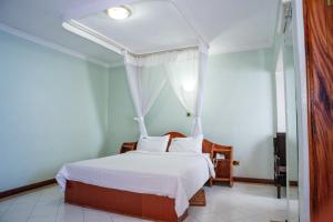 内罗毕Jupiter Guest Resort - Langata的一间卧室配有带白色床单和枕头的床。