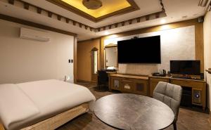 首尔Doksan 3S Hotel的一间酒店客房,配有一张床铺、一张桌子和一台电视