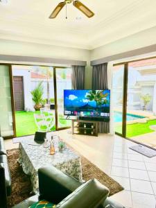 乔木提恩海滩Pattaya Jomtien Private Luxury Pool Villa 芭堤雅中天豪华私家泳池别墅的客厅配有大屏幕电视和沙发。