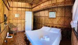 波尔多·格尼拉Bamboo House Beach Lodge & Restaurant的卧室配有一张床铺,位于带木墙的房间内