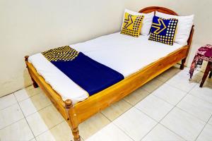 GresikOYO 93108 Homestay H Syarif Syariah – RA Kartini的一张带蓝色和黄色枕头的木床